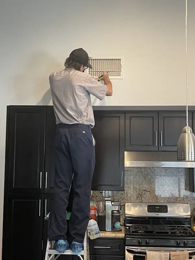 Technician inspecting an air vent during HVAC service in Taylor